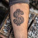 Dollar symbol tattoo on man's forearm
