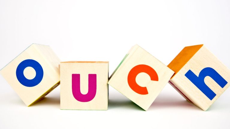 Alphabet blocks spelling out the word ouch against a white background